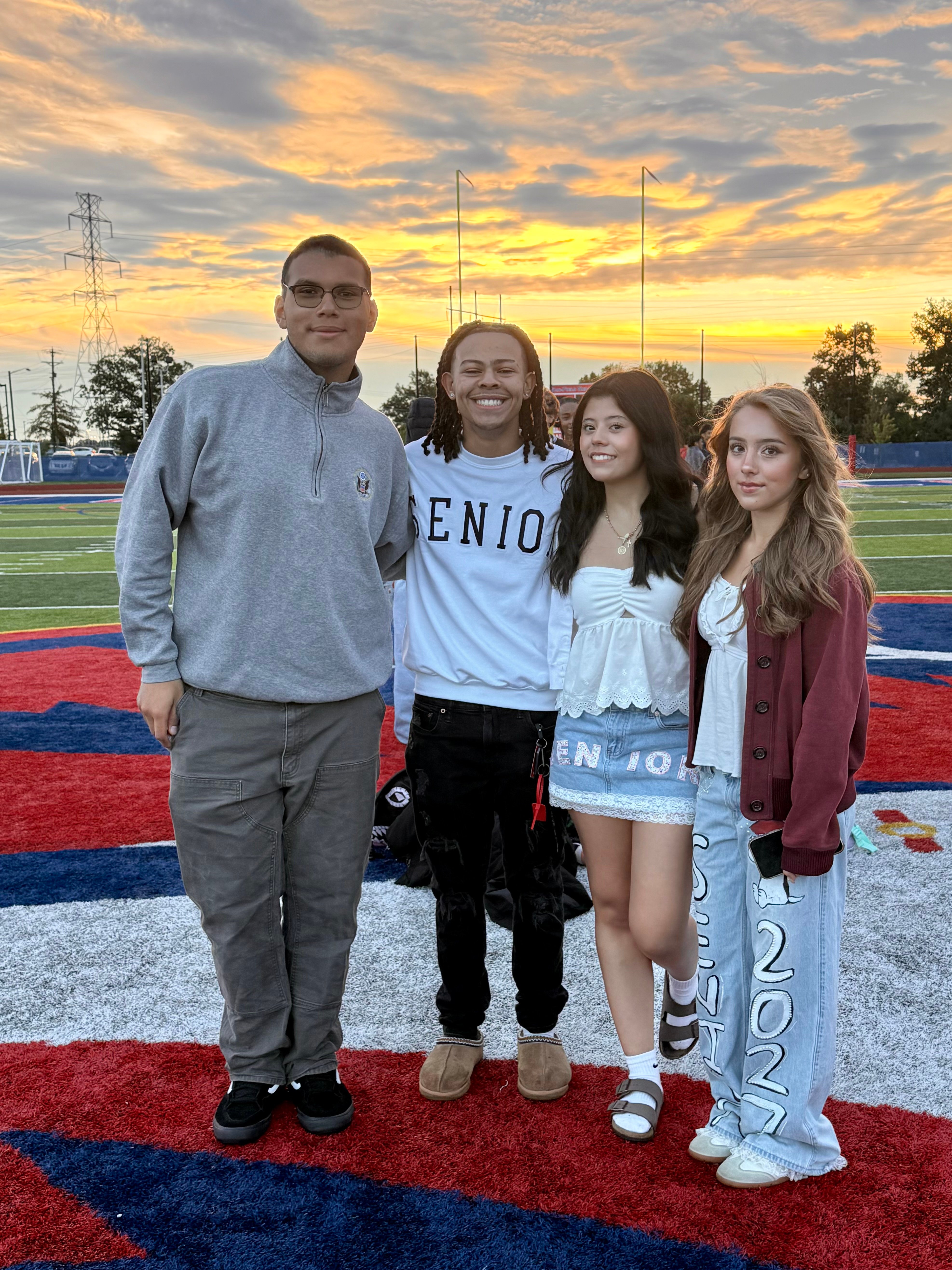 Class officers Ceylin Deherrera, Alejandra Membreno, Carter Lewis, and Steven Canales stand smiling on the football field. 